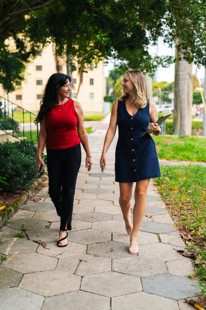 Stephanie Meid and Isabel Allen of Team Sigh walking along a brick-paver sidewalk